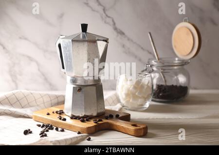 Mokakanne und Kaffeebohnen auf weißem Holztisch, Platz für Text Stockfoto