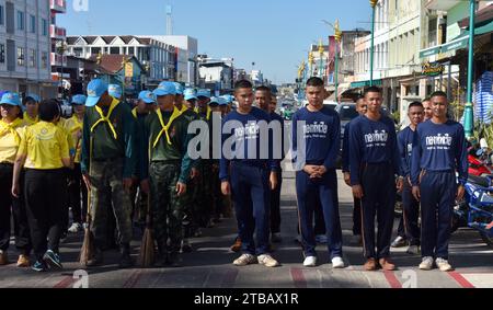 Soldaten der Royal Thai Army (links in grünen Hemden), Seeleute der Royal Thai Navy (rechts in blauen Hemden) und andere Leute parieren vor einem nationalen Aufräumtag in Nakhon Phanom, Thailand, Südostasien. Der 5. Dezember ist ein Nationalfeiertag, da er an den Geburtstag des verstorbenen Königs Bhumibol Adulyadej, Rama 9, erinnert. Die Veranstaltung beginnt mit einer Parade für Fotos und kurze Reden, gefolgt von allen, die Zweigbürsten und Wassertanker verwenden, um die Straßen sauber zu fegen. Der Tag ist in Thailand als Vatertag bekannt. Nakhon Phanom, Isaan, Thailand, Asien Stockfoto