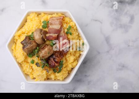 Gekochtes Maismehl mit Speck, Pilzen und Mikrogrün in Schüssel auf weißem Marmortisch, Blick von oben. Leerzeichen für Text Stockfoto