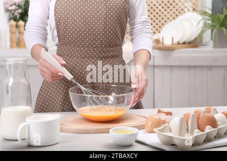 Frau, die Eier in einer Schüssel an einem Tisch drinnen rausquetscht, Nahaufnahme Stockfoto