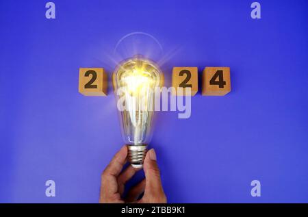 Leuchtender Kalender 2024, kreative Trendlampe, die von Geschäftsmanns Hand gehalten wird und leuchtend leuchtet. Digitales Netzwerk und luxuriöser Hintergrund. Frohes Neues Jahr 20 Stockfoto