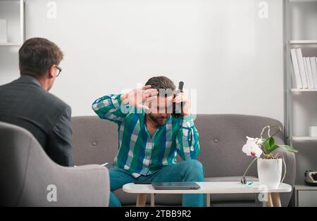 Verärgerter Mann Alkoholiker sitzt bei Psychologen auf Psychotherapiesitzung, trauriger depressiver, betrunkener Kerl, der Probleme mit Alkoholmissbrauch hat, al Stockfoto