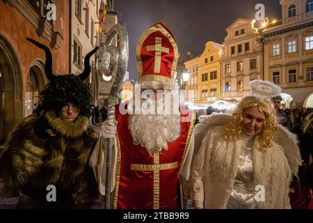 Prag, Tschechische Republik. Dezember 2023. Als Heiliger Nikolaus (C), Teufel (L) und Engel (R) gekleidet auf dem Altstädter Ring in Prag. Die Tradition des Heiligen Nikolaus in Tschechien, genannt Svaty Mikulas, wird in vielen europäischen Ländern gefeiert. Es wird vermutet, dass der Heilige Nikolaus kommt, um seinen Tag zu feiern und vor Weihnachten abreist. Künstler spazieren durch das Stadtzentrum und wünschen den Menschen frohe Weihnachten und belohnen Kinder mit kleinen Geschenken. Quelle: SOPA Images Limited/Alamy Live News Stockfoto