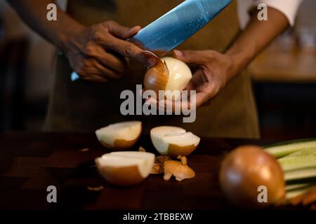 Frauenhände mit einem scharfen Messer, das weiße Zwiebeln in der Küche schält. Stockfoto