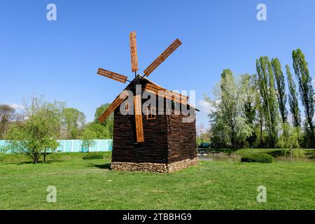 Dekorative alte Holzmühle und grünes Gras auf einer kleinen Insel auf dem See vom Chindiei Park (Parcul Chindiei) in Targoviste, Rumänien, in einem sonnigen SPR Stockfoto