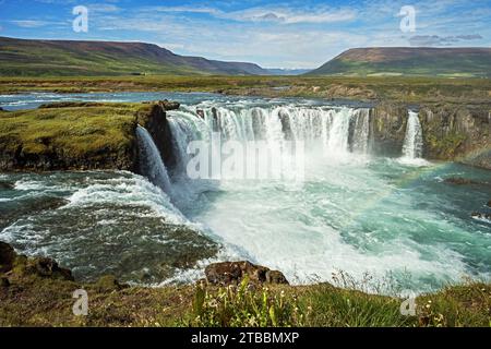 Der Fluss Skjalfandafljot stürzt über den Godafoss Wasserfall in Nord-Island mit einem teilweise bewölkten Himmel im Hintergrund Stockfoto