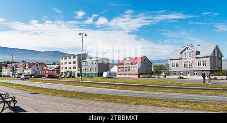 Breiter Fußweg auf einer angenehmen Straße, gesäumt von kleinen Apartmenthäusern in Akureyri Island unter einem teilweise bewölkten Sommerhimmel Stockfoto