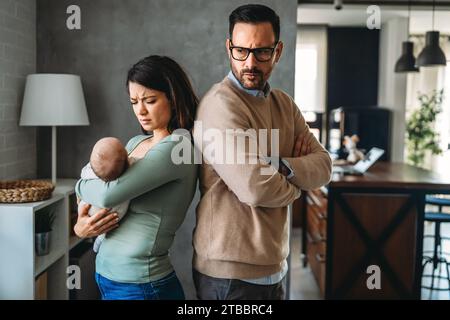 Junger Vater mit Baby und Frau, die zu Hause an postnataler Depression leidet Stockfoto