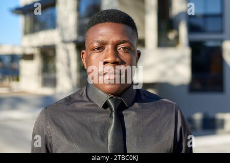 Porträt des jungen schwarzen Geschäftsmannes, der ein schwarzes Hemd und eine Krawatte trägt Stockfoto