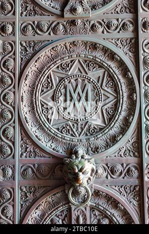 Details bilden eine alte Kirchentür mit Löwenkopf und Blumenverzierungen Stockfoto