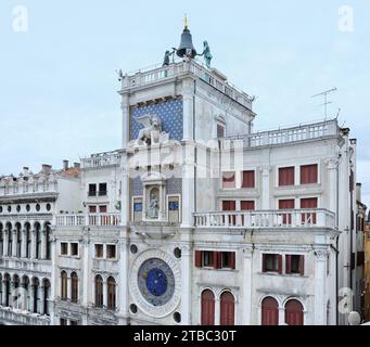 Markusuhrturm Venedig, Tierkreisuhr, Glockenturm, Markuslöwe und angrenzende Apartments von der Markuskirche Stockfoto