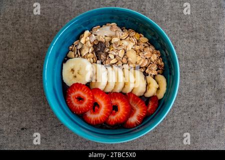 Ein Bild aus der Vogelperspektive einer Schüssel Acai-Eis mit frischem Obst und Haferflocken aus nächster Nähe. Stockfoto