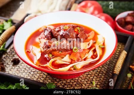 Scharfe rote Suppe Rindernudeln in einer Schüssel auf weißem Hintergrund, biang biang Nudeln Stockfoto