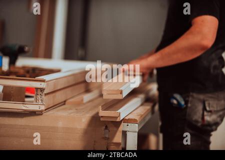 Ein Facharbeiter in der Holzbearbeitungsindustrie nutzt moderne Maschinen, um Holztüren für den Markt zu verarbeiten und vorzubereiten Stockfoto