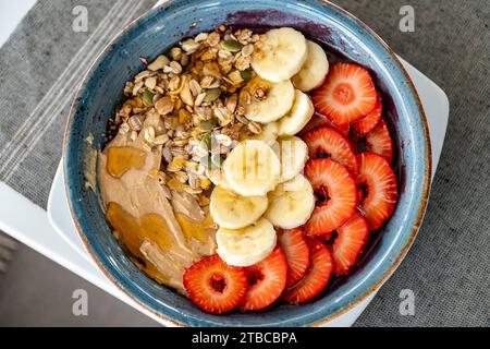 Eine Schüssel Acai-Eis mit frischem Obst und Nüssen aus der Vogelperspektive aus der Nähe Stockfoto