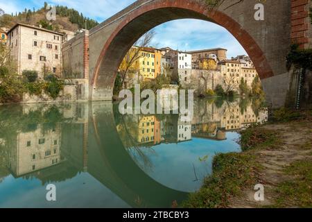 Blick auf Fossombrones charmante Altstadt vom Park aus, mit der Ponte della Concordia, die sich über den Metauro-Fluss erstreckt. Stockfoto