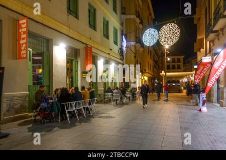 Außenterrasse mit Leuten im Winter, Blick auf die Straße bei Nacht, Malaga, Andalusien, Spanien. Stockfoto