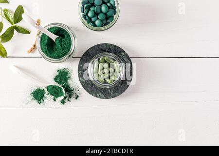 Drei Gläser mit Spirulina-Produkt aus organischen grünen Algen in Tabletten, Kapseln, Pulver. Eine Alternative zur Medizin. Draufsicht. Weißer Hintergrund Stockfoto