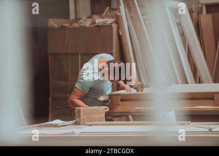 Ein Facharbeiter in der Holzbearbeitungsindustrie nutzt moderne Maschinen, um Holztüren für den Markt zu verarbeiten und vorzubereiten Stockfoto