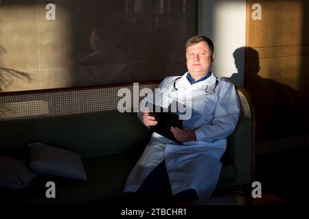 Ein müder Arzt arbeitet bis zum Morgengrauen mit Dokumenten in seinem Büro. Stockfoto