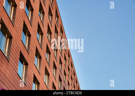 Die moderne orange gemauerte Fassade mit Fenstern gegen den Himmel ist ein Beispiel für eine gepflegte Architektur. Modernes Äußere mit großen orangen Ziegeln Stockfoto