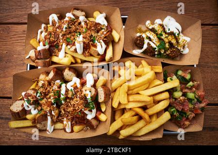 Blick von oben auf das traditionelle Gericht Kurry Korv und Falafel oder typisch deutsche Currywurst mit Falafel serviert auf einem Holztisch und Papierteller Stockfoto