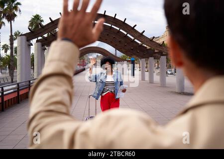 Afroamerikanerin begrüßt ihren Freund nach langer Trennung mit Gepäck im Freien. Stockfoto