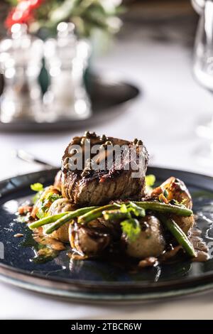 Filet-Steak aus Rinderfilet, sautierte grüne Bohnen mit Speck, gebackene Kartoffeln und grüne Pfeffersoße. Filet Steak serviert auf einem Teller auf einem fest Stockfoto