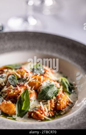 Gnocchi Pomodoro mit Mascarpone, Creme, Basilikum und Parmesan auf einem stilvollen Teller auf einem Restauranttisch. Stockfoto