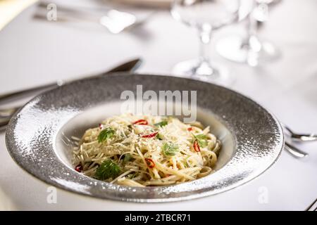 Italienische Spaghetti Algio e Olio mit Knoblauch-Parmesan und Chili-Paprika auf festlichem Tisch im Restaurant. Stockfoto