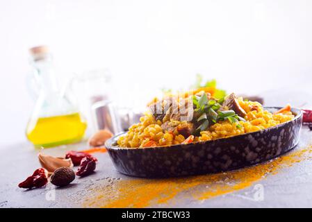 Pilaw, ein Gericht mit Reis, Huhn, Karotten mit Gewürzen und getrockneten Preiselbeeren auf einem schwarzen Teller auf einem Tisch. Östliche Küche. Stockfoto