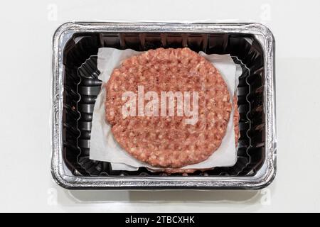 Rohe Hamburger Hackfleisch-Pastete in Plastikverpackung, verpackte Lebensmittel, Fast Food. Verkauf fertiger Lebensmittel. Isolierter weißer Hintergrund, Draufsicht Stockfoto