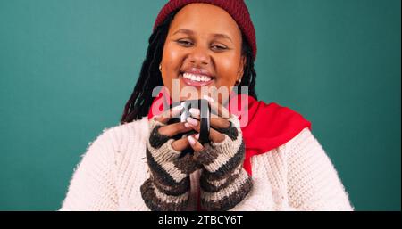 Schöne junge Frau trinkt im Winter ein warmes Getränk, weihnachtliches Farbenstudio Stockfoto
