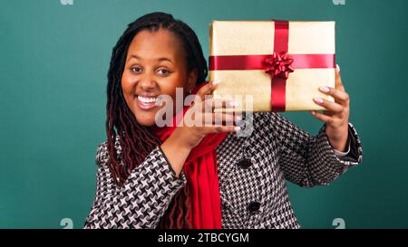Die aufgeregte junge Frau hält eine Geschenkbox und zeigt das Gesicht, das Weihnachtsgeschenk-Studio Stockfoto