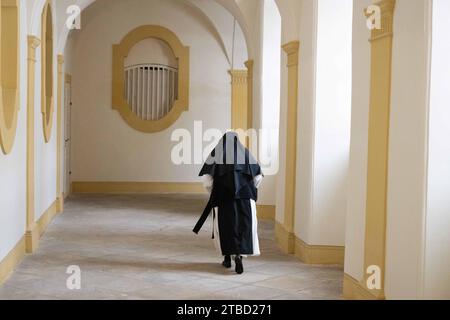 Ostritz, Deutschland. Dezember 2023. Elisabeth Vaterodt OCist, Äbtissin von St. Marienthal Kloster, Spaziergänge entlang eines Kreuzgangs im Kloster. Sachsen hat die historisch wertvolle Bibliothek St. Kloster Marienthal für 5,5 Millionen Euro. Quelle: Sebastian Kahnert/dpa/Alamy Live News Stockfoto