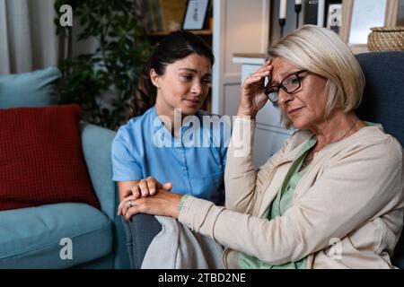 Junge Frau Arzt Gesundheitspersonal medizinische Krankenschwester tröstet ältere ältere Frau zu Hause Besuch, Patient leidet an klinischen Depressionen und Angst. Stockfoto