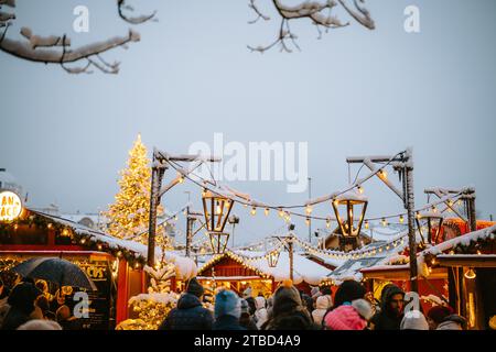 02.12.2023 Zürich, Schweiz. Leute, die Anfang Dezember bei Schneefall einen Weihnachtsmarkt besuchen. Spätabendliches Licht, Weihnachtsdekoration. Stockfoto