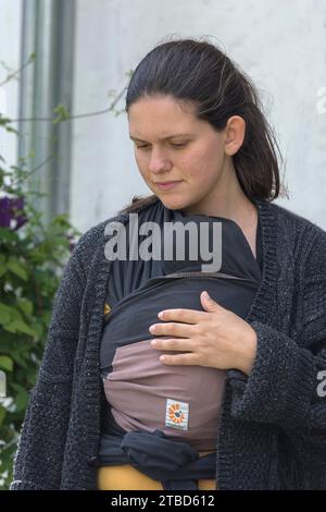 Junge Mutter mit ihrem Baby in einer Schlinge, Mecklenburg-Vorpommern, Deutschland Stockfoto