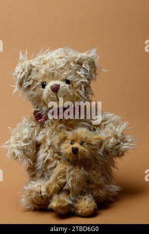 Zwei Teddybären sitzen vor braunem Hintergrund, Teddy Stockfoto