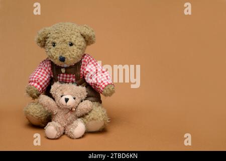 Zwei Teddybären sitzen vor braunem Hintergrund, Teddy Stockfoto