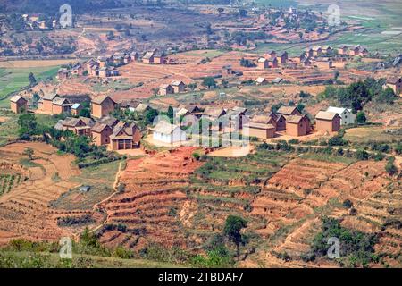 Terrassenfelder und zweistöckige Backsteinhäuser im ländlichen Dorf Betsileo im Bezirk Ambositra, Region Amoron'i Mania, Zentralmadagaskar, Afrika Stockfoto