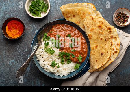 Traditionelles indisches Punjabi-Gericht Dal makhani mit Linsen und Bohnen in schwarzer Schüssel, serviert mit Basmati-Reis, Naan-Fladenbrot, frischem Koriander und Löffel Stockfoto