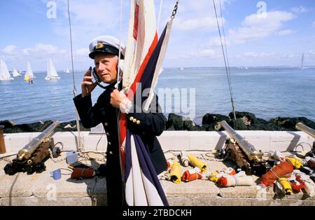 Cowes Sailing Regatta, alle Rennen werden gestartet, wenn die kleinen Kanonen abgefeuert werden. Verschiedene Flaggen, die Wettbewerbern Informationen zum Rennsport anzeigen. Die Kanonen vor dem Gebäude der Royal Yacht Squadron stammen von Royal Adelaide, einer der Yachten von King William IVs, und der Rennoffizier, der sie feuert, ist bekannt als der Gunner. Cowes, Isle of Wight, Hampshire England, 1985 1980. August, Großbritannien HOMER SYKES Stockfoto