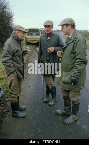 Fasanenschießen. Burley on the Hill, ein Spiel, ein Vogelschießen auf dem privaten Landgut. Schützen unterhalten sich in einer Pause in den Tagen Sport, trinken aus silbernen Bechern. Burley on the Hill, Oakham, Rutland, England, 1985 1980er Jahre HOMER SYKES Stockfoto