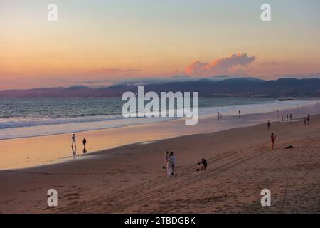 Menschen, die den Sonnenuntergang am Strand von Venedig in Los Angeles, Kalifornien, genießen. Stockfoto