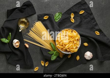Komposition mit verschiedenen rohen Nudeln und Gewürzen auf dunklem Hintergrund Stockfoto