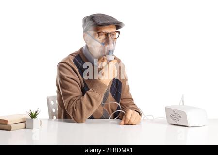 Älterer Mann, der auf einem Tisch sitzt und einen Vernebler mit Dampfnebel auf weißem Hintergrund benutzt Stockfoto