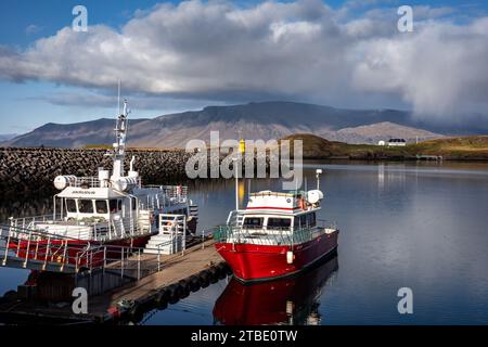 Reykjavik, Island - 06. Oktober 2023: Atlantikküstenlandschaft mit Videy Island und Esja Berg. Rote Fährschiffe im Vordergrund. Stockfoto