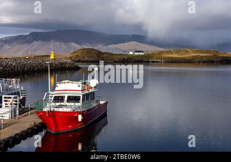 Reykjavik, Island - 06. Oktober 2023: Atlantikküstenlandschaft mit Videy Island und Esja Berg. Rote Fährschiffe im Vordergrund. Stockfoto