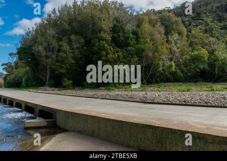 Fahrzeughintergrund oder Rückwand mit einer Landstraße mit einer niedrigen Brücke, die über einen Fluss oder Fluss führt Stockfoto